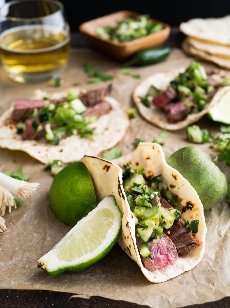A table covered in tacos, lime slices, and drinks