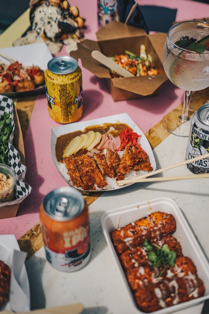 A table covered in takeout food and canned drinks
