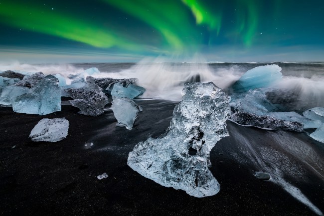 Northern lights over famous Diamond beach, Iceland. This sand lava beach is full of many giant ice gems, placed near glacier lagoon Jokulsarlon Ice rock with black sand beach in southeast Iceland