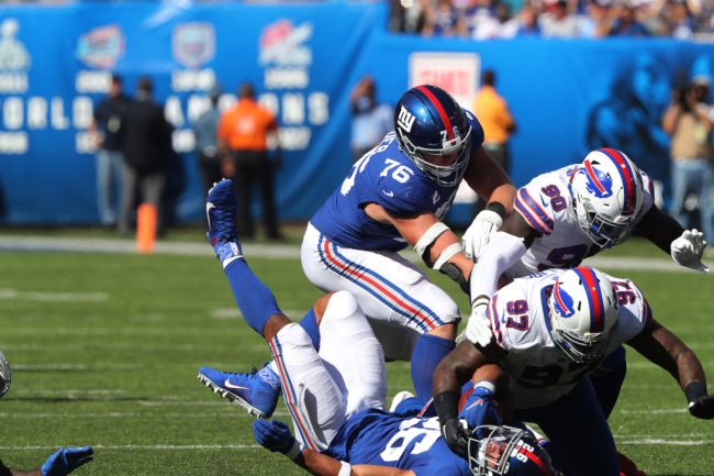 EAST RUTHERFORD, NEW JERSEY - SEPTEMBER 15: Safety Siran Neal #33 and Defensive Tackle Jordan Phillips #97 of the Buffalo Bills upend Running Back Saquon Barkley #26 of the New York Giants in the Second Half at MetLife Stadium on September 15, 2019 in East Rutherford, New Jersey.