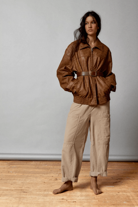 A model wearing a brown leather jacket and beige cargo pants