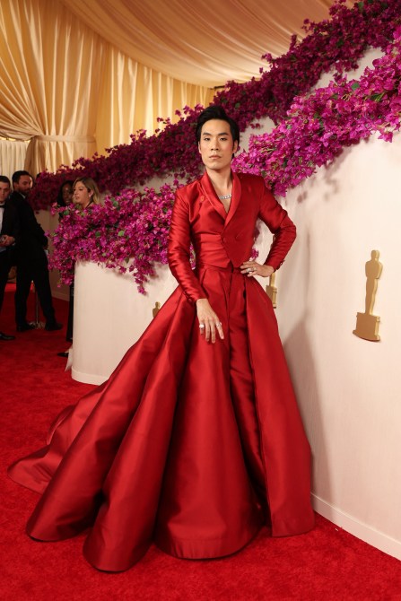 Eugene Lee Yang on the 2024 Oscars red carpet in a red blazer and matching red skirt