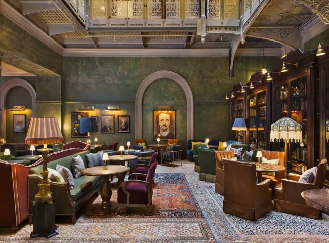 The lobby at The Beekman Hotel, which features green walls, printed rugs, and lots of traditional furniture
