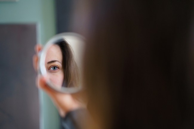 Woman looking at her reflection in the mirror