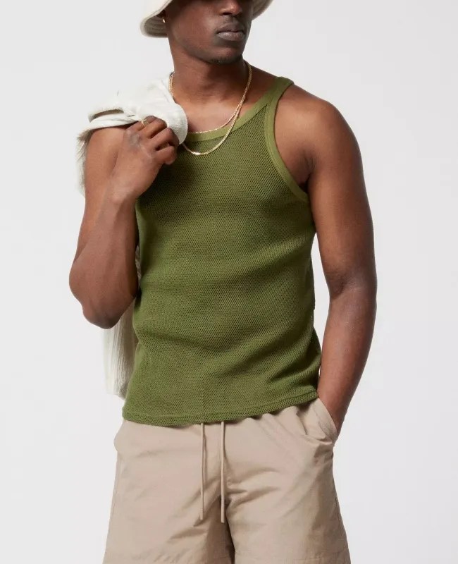 A person wearing a Urban Outfitters green mesh tank.