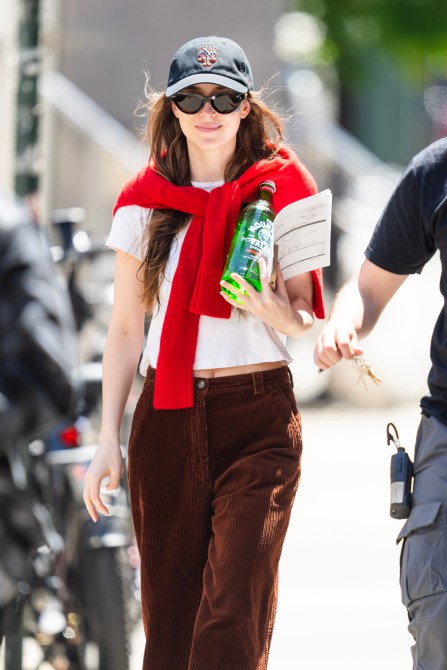 Dakota Johnson wearing a Mets cap and a red cardigan tied around her shoulders.