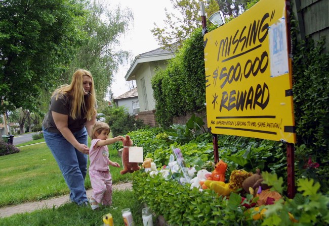 Brandi Dessayer helps her daughter Danielle Dessayer place a stuffed animal outside Laci and Scott Peterson's home April 15, 2003 in Modesto, California. Investigators said it would take several days or weeks to identify the bodies of a woman and baby found on a beach 90 miles northwest of Modesto. Peterson has been missing since Christmas Eve 2002.