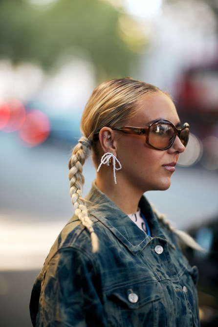 A fashion week guest wearing pearl bow earrings.