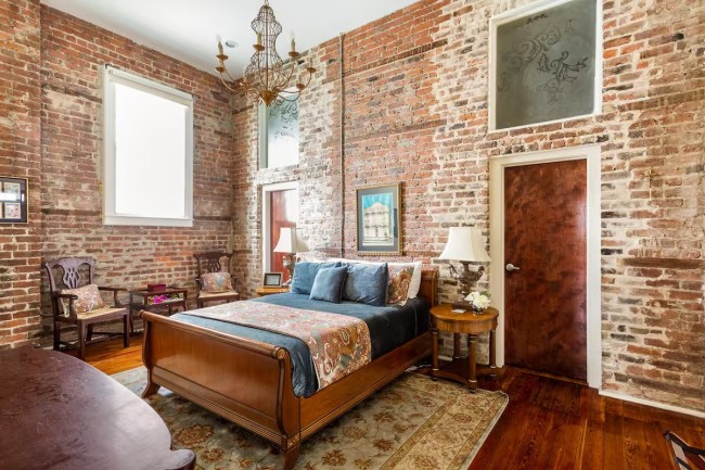 Bedroom with a chandelier and brick wall