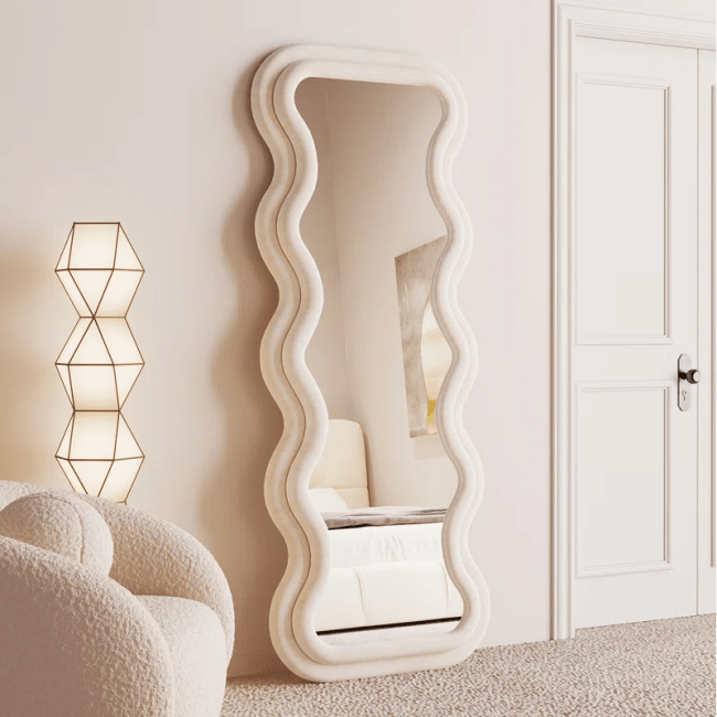 A cream-colored room with a tall, wavy mirror