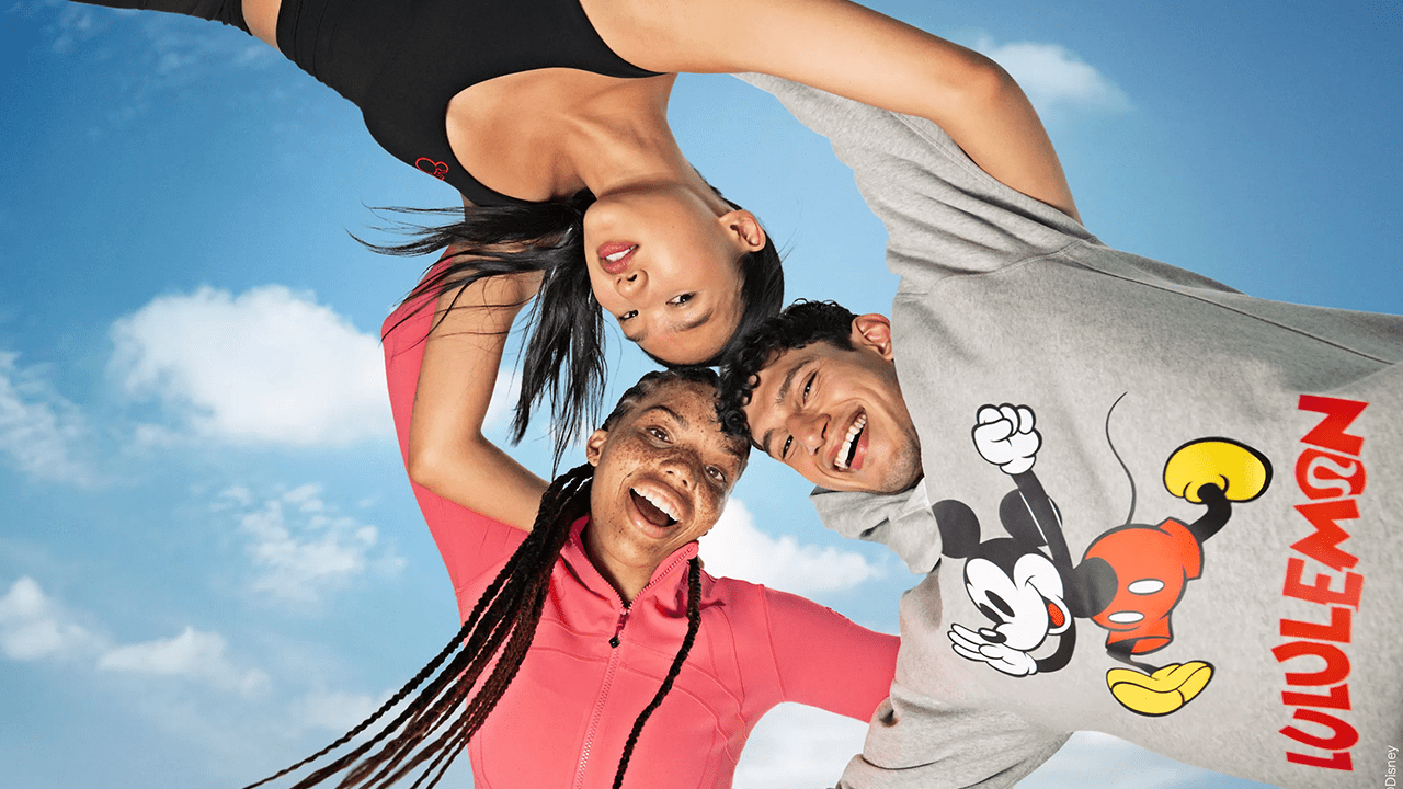 Three models with their arms around each other wearing the Disney x Lululemon collection