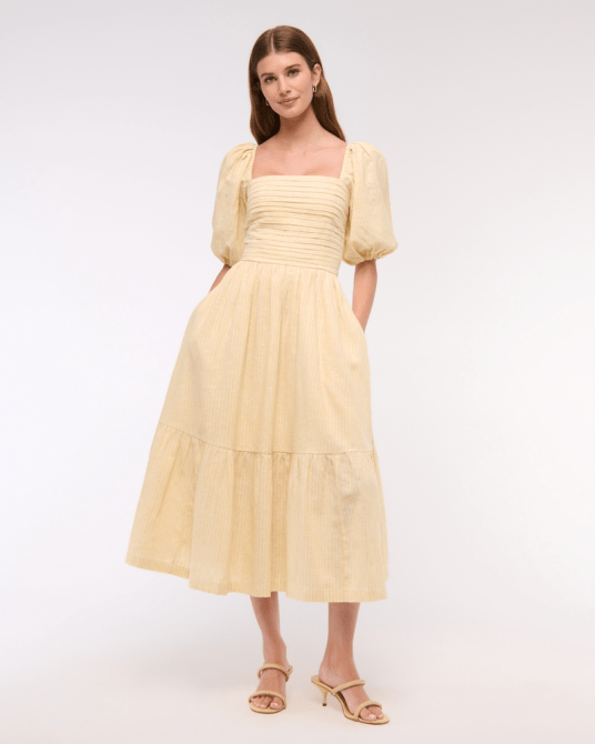 A model wearing the Abercrombie & Fitch Emerson Linen-Blend Puff Sleeve Midi Dress in a butter yellow and white vertical stripe print